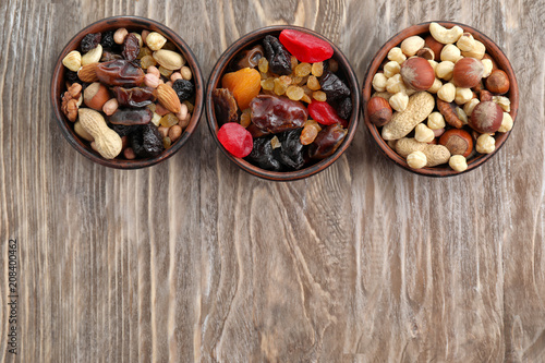 Bowls with mix of dried fruits, berries and nuts on wooden background, top view