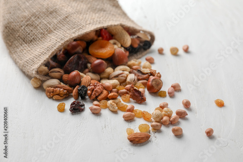 Fototapeta Naklejka Na Ścianę i Meble -  Sackcloth bag with mix of nuts and dried fruits on light background