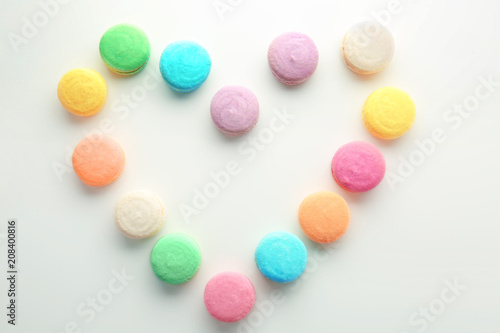 Heart made with tasty macarons on white background