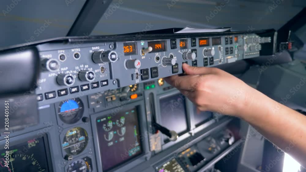 Multiple buttons on a plane's console are being pushed and rotated by a pilot Multiple buttons on a plane's console are being pushed and rotated by a pilot