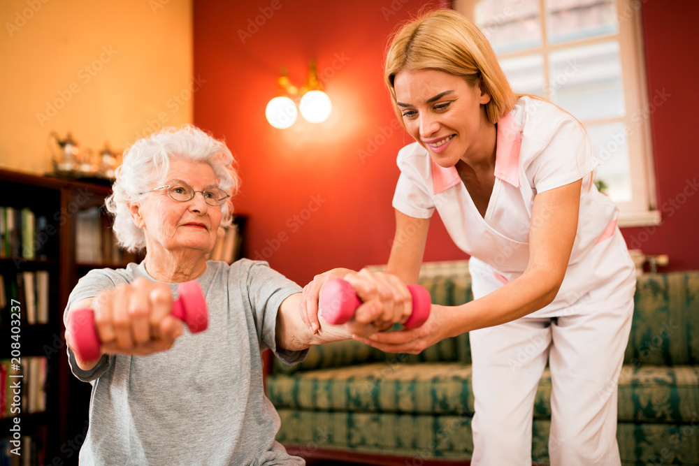 Fototapeta premium Smilinig positive senior woman enjoy in exercise with nurse