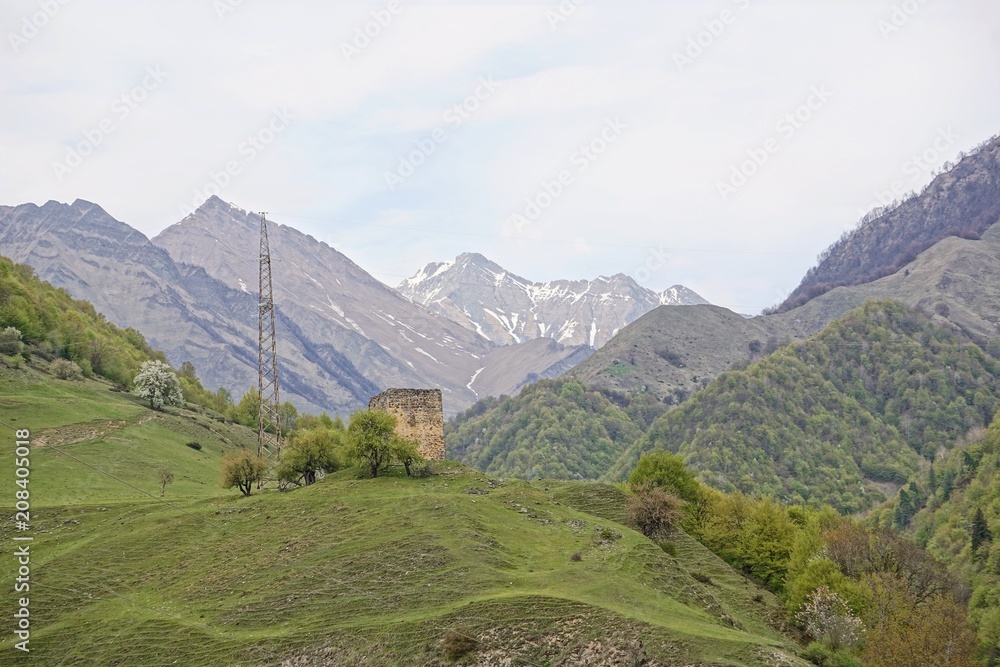 Naklejka premium Mountain landscape with an ancient signal tower on the Georgian Military Road in the valley of the Terek river, horizontal image, Caucasus, Georgia (Europe)
