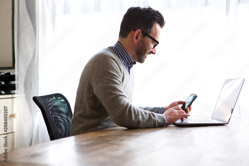 older man working at home with laptop and mobile phone older man working at home with laptop and mobile phone