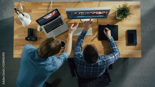 Top View of Two Young Talented Photographers Discussing Footage. One of Them Works on a Digital Drawing Tablet at His Desktop Computer. Processing Wedding Photography.