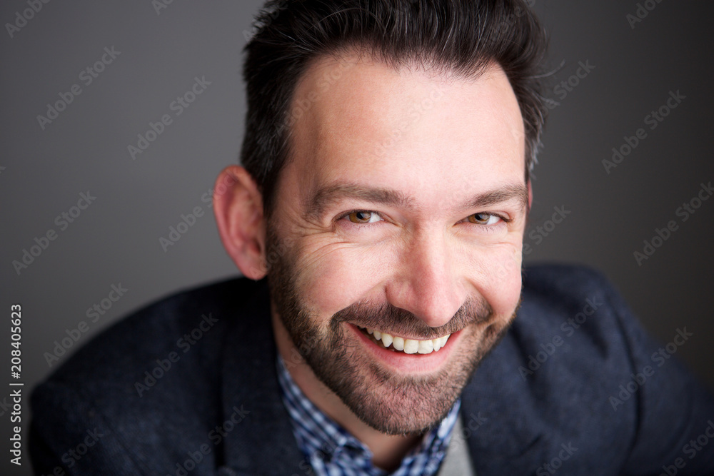 Close up businessman with beard smiling abasing gray wall