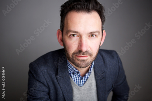 Close up businessman with beard against gray wall
