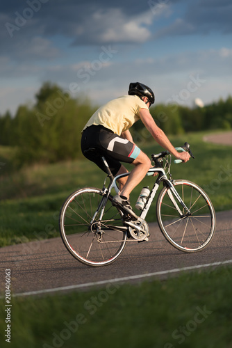 Cyclist man riding road sport bike in sunny day on a mountain road