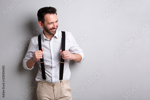 Foto middle age man with suspenders smiling against gray background