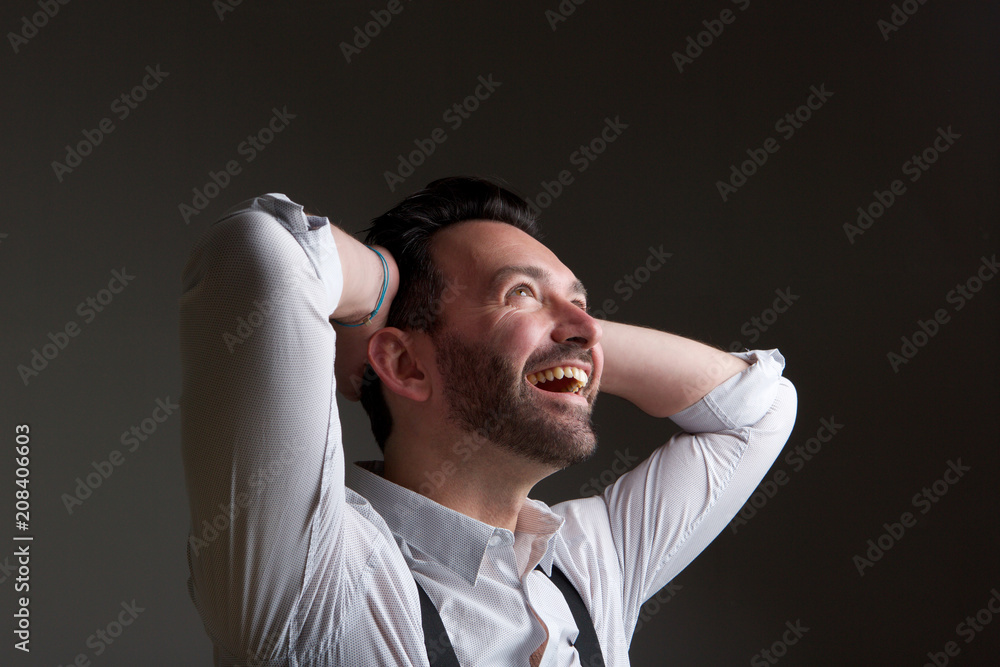 happy man with beard laughing with hands behind head