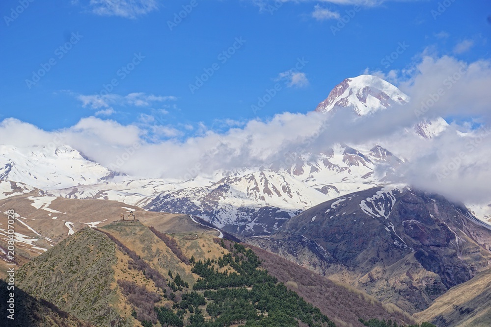 View of the glacier peak Kazbek in the clouds and Gergeti Trinity Church, Caucasus, Kazbegi District, Georgia (Europe) View of the glacier peak Kazbek in the clouds and Gergeti Trinity Church, Caucasus, Kazbegi District, Georgia (Europe)