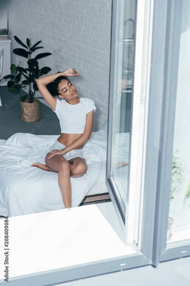 attractive young woman sitting on bed in morning at home attractive young woman sitting on bed in morning at home