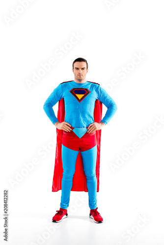 full length view of handsome mid adult superman standing with hands on waist and looking at camera isolated on white