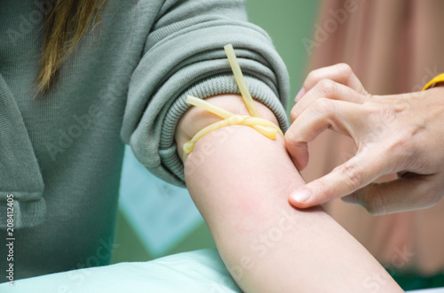 Nurse is preparing to draw blood sample from the patient's arm for blood test