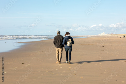 A woman and a man are walking on a sunny day along the beach in Katwijk. Netherlands