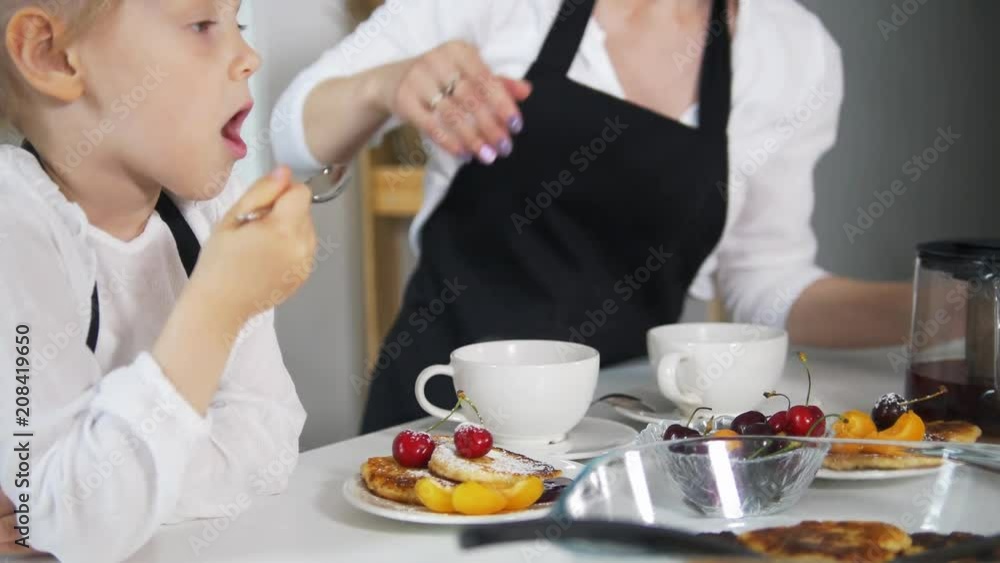 Little girl with her mother drink tea with homemade cottage cheese pancakes Little girl with her mother drink tea with homemade cottage cheese pancakes