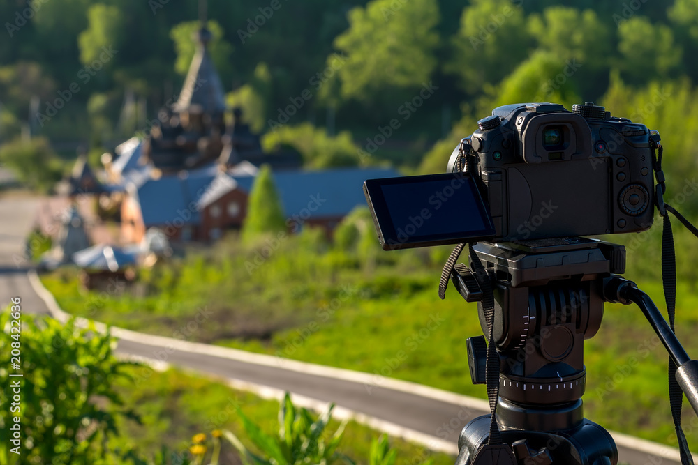 camera on a tripod shoots a wooden Church in the early morning