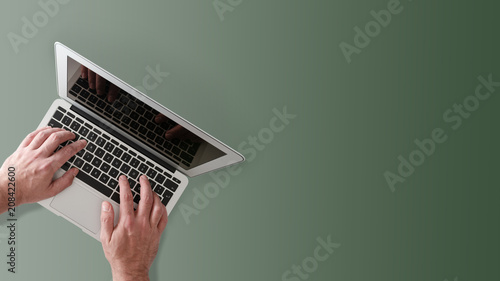 top view of man typing on notebook computer on desktop