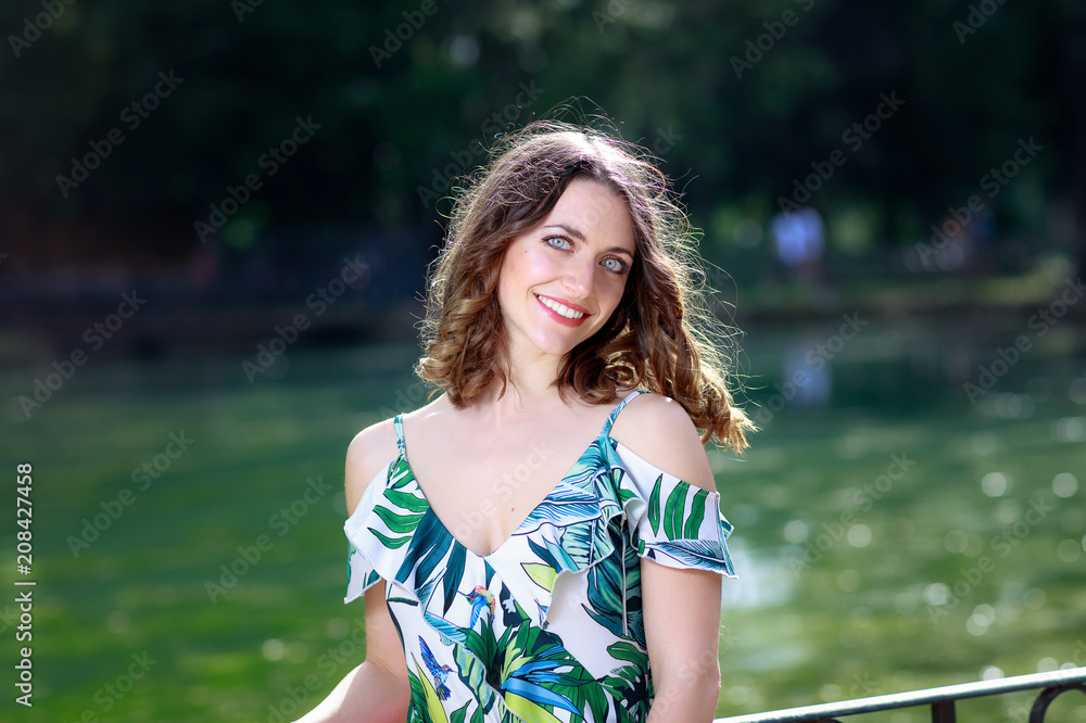 Portrait of a young woman by the green lake, in the park outdoors. Portrait of a young woman by the green lake, in the park outdoors.