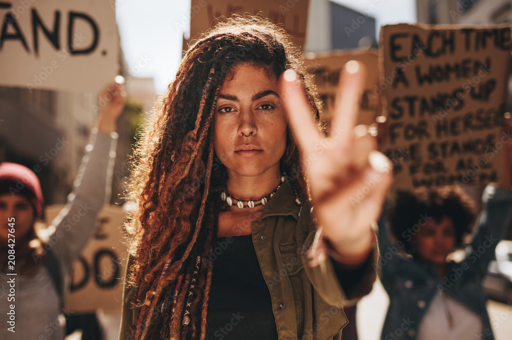 Woman showing a peace sign during protest - obrazy, fototapety, plakaty 