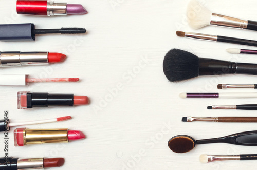 Make up or visage background. Different cosmetic accessories on white table. Collection of various lipstick and brushes on the table.