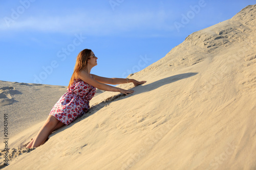 Piękna rudowłosa dziewczyna wypoczywa na piaszczystych wydmach.