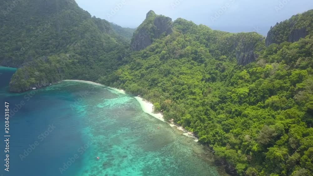 Aerial drone view of a beautiful tropical sandy beach and coral reef on a jungle covered island