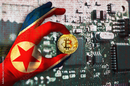 Bitcoin crypto currency North Korea flag Binary code Golden Coin of Bitcoin in the Northern Korea flag hand between two fingers shows OK sign on a chip background with matrix effect