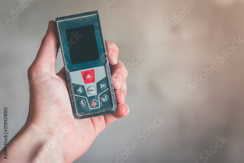 Wallpaper Mural Hand holding construction roulette, calliper and laser range finder on wall background. Laser measuring tool. Torontodigital.ca