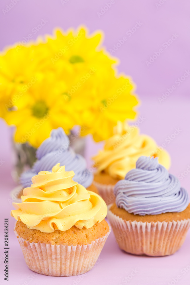 Cupcakes decorated with yellow and violet cream and chrysanthemums on violet pastel background for greeting card with copyscape. Cupcakes decorated with yellow and violet cream and chrysanthemums on violet pastel background for greeting card with copyscape.