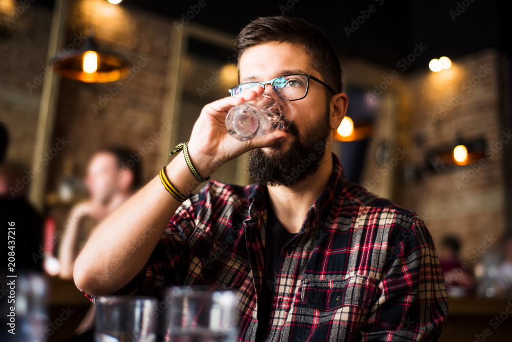 Bearded man drinking water in a coffee bar