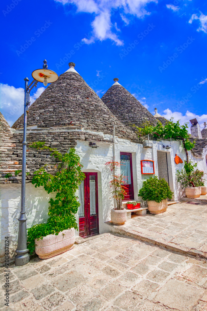 Fototapeta premium Alberobello, Puglia, Italy: Typical houses built with dry stone walls and conical roofs, in a beautiful day, Apulia