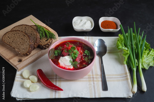 Traditional Ukrainian Russian borscht with beans on the bowl. Plate of red beet root soup borsch on black table.