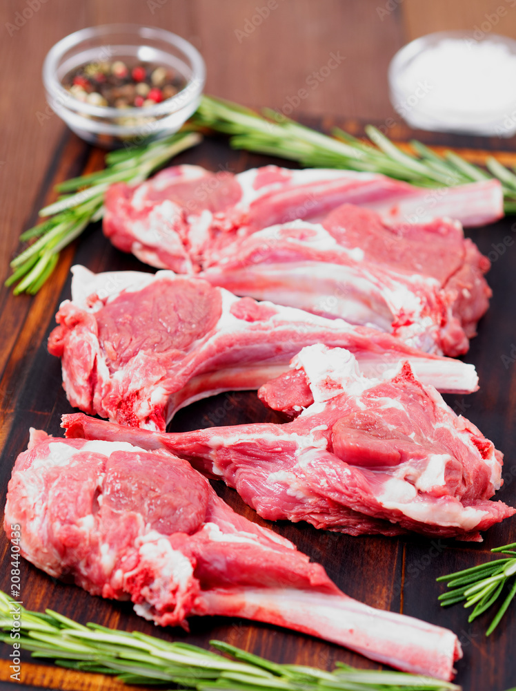 Raw lamb cutlets on bone on dark brown wooden background, lamb ribs, side view, vertical