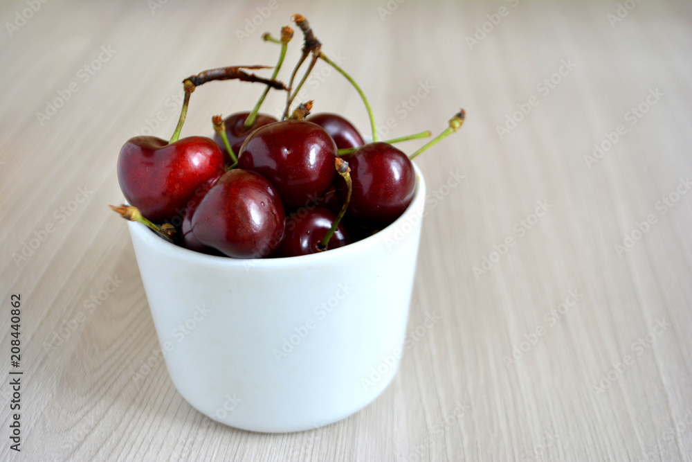 Cherry in white cup on wooden background Cherry in white cup on wooden background