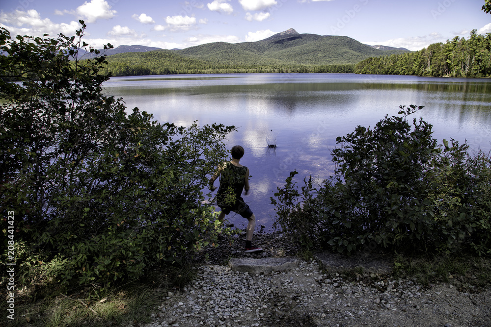 young man playing by lake in summer