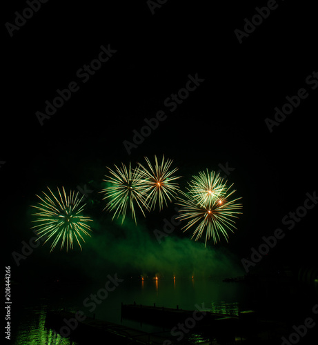 Beautiful colorful fireworks display on celebration night Celebration fireworks over the river with cityscape soft focus background at night scene