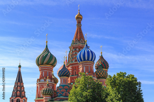 Domes of St. Basil's Cathedral on Red square in Moscow against green trees on a sunny summer morning