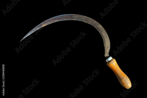 Old dirty metal sickle with a wooden handle. Close-up. Isolated object on a black background. Isolate. photo