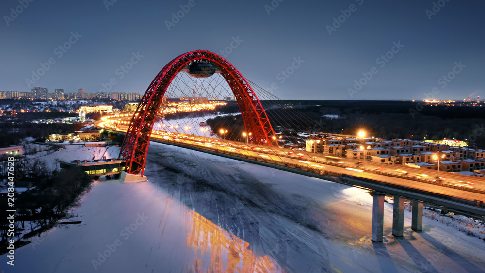Obraz premium Flying around the Picturesque Bridge over the Moskva river at dusk. Aerial dolly shot of the intense traffic on the illuminated bridge over the frozen river.