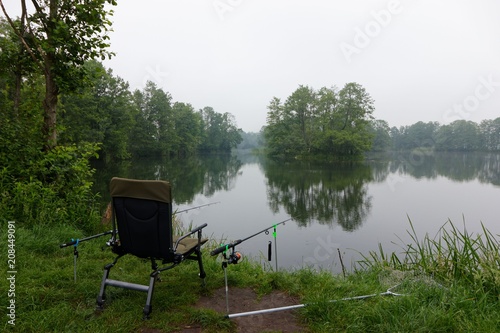 Fishing chair and fishing rods on the shore of a lake