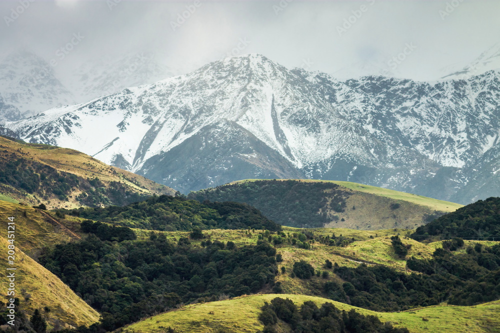 Snow covered mountains and green rolling hills of New Zealand