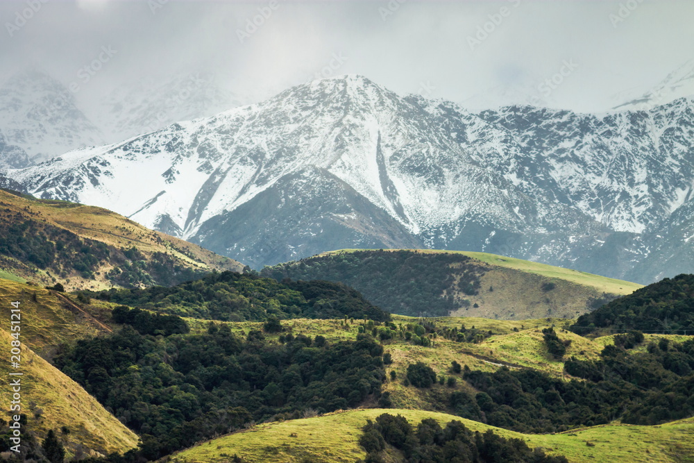 Snow covered mountains and green rolling hills of New Zealand Snow covered mountains and green rolling hills of New Zealand