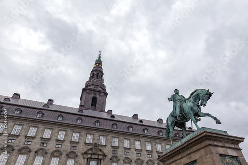 Moody wide angle view of the Christiansborg Palace and Frederik VII Statue in Copenhagen, Denmark.
