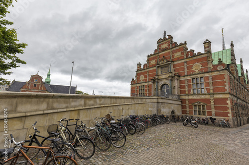 Classic view of Copenhagen with traditional architecture, bicycles and cloudy sky.