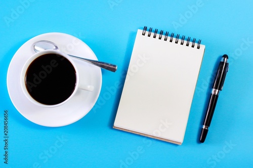 Flat lay photo with notebook , coffee cup and Pen on blue background