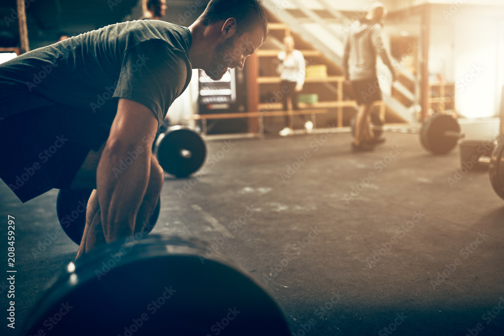 Naklejka premium Young man preparing to lift weights during an exercise class