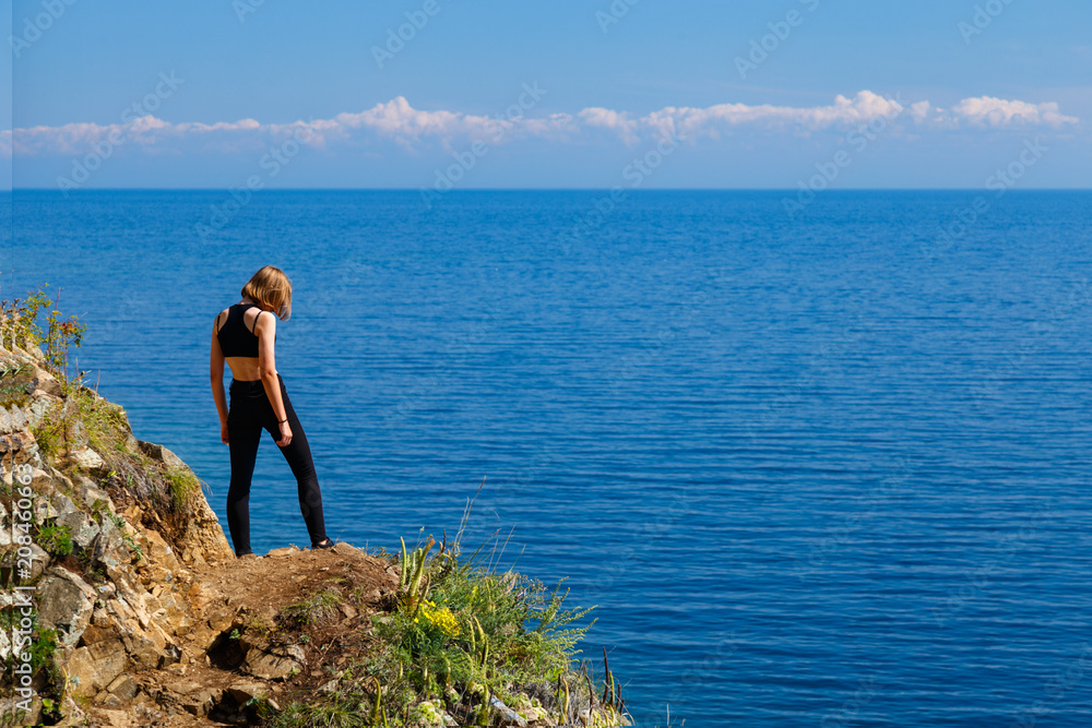 A teenage girl standing at Baikal lake shore
