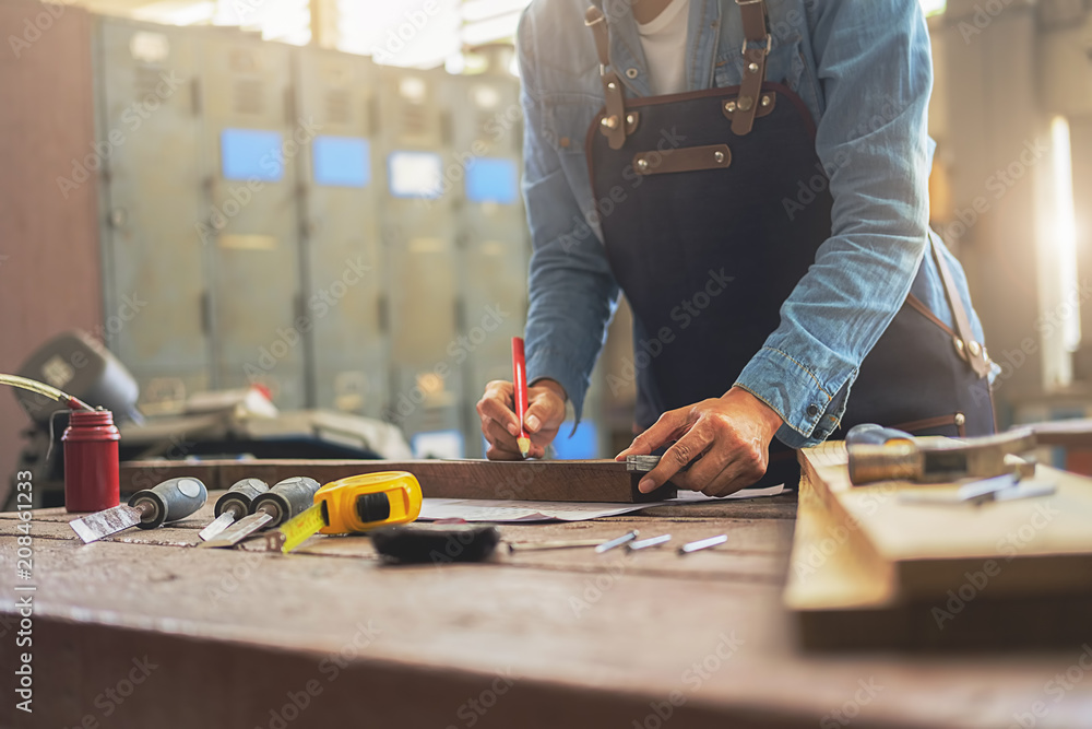 Carpenter working on woodworking machines in carpentry shop. A man works in a carpentry shop. Carpenter working on woodworking machines in carpentry shop. A man works in a carpentry shop.