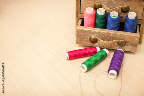 Sewing threads multicolored in wooden box background closeup with space for text