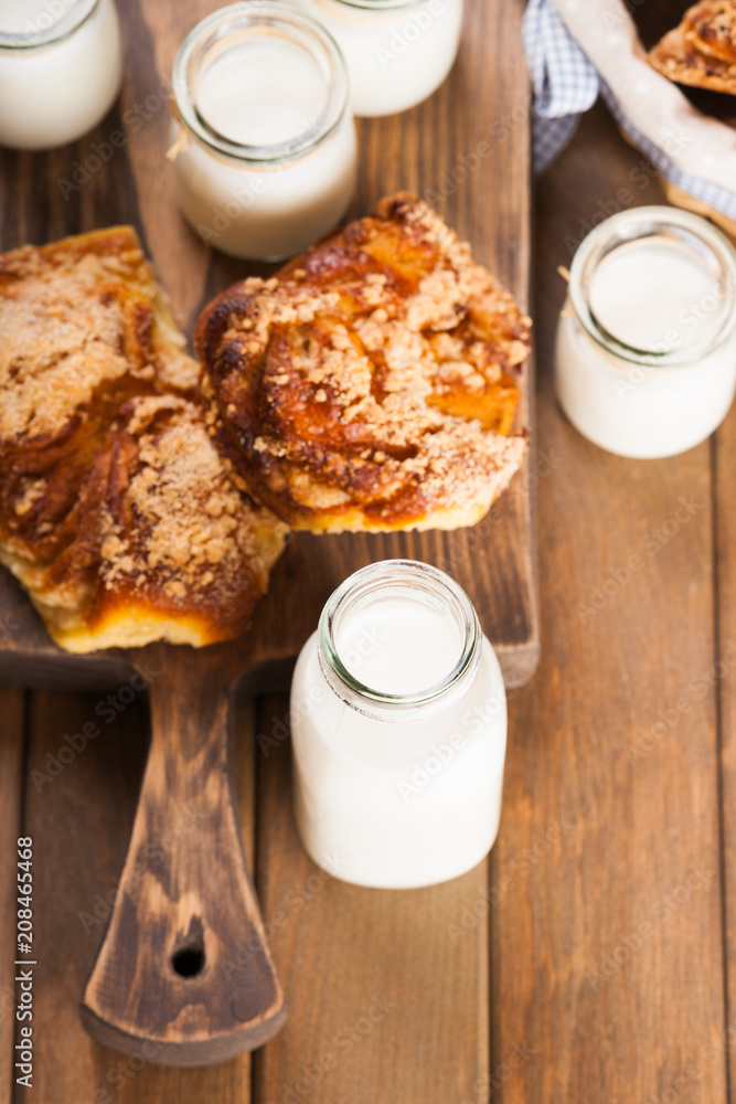Jars with milk and bread buns on a cutting board Jars with milk and bread buns on a cutting board